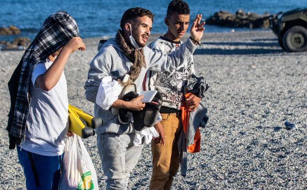 Imagen principal - Brahim, en el centro, a su llegada a la playa del Tarajal (arriba), varios inmigrantes asistidos por el Ejército y Cruz Roja.