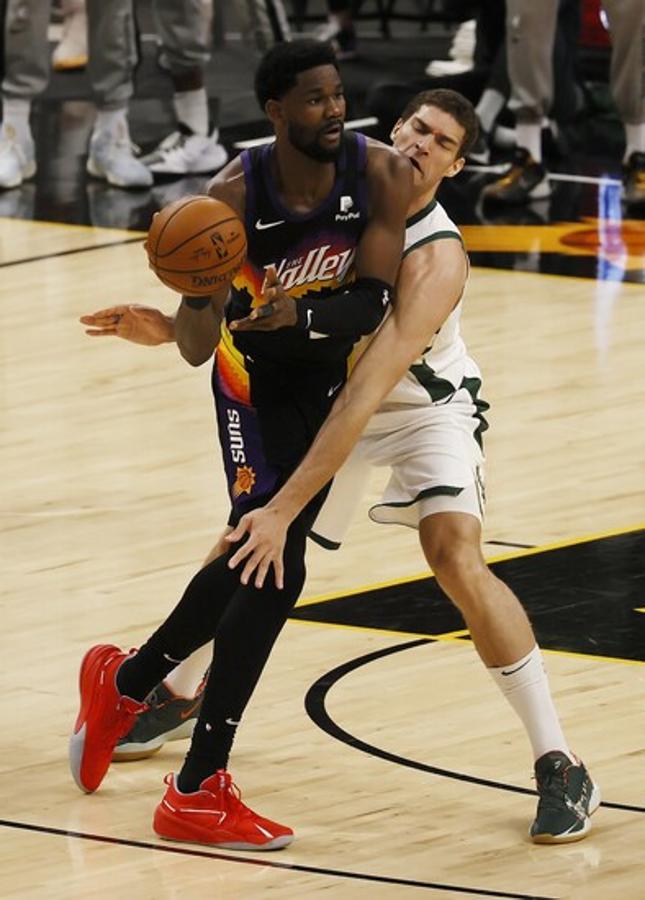 El jugador de los Suns ,Deandre Ayton a punto de hacer un pase con Brook Lopez presionando. 