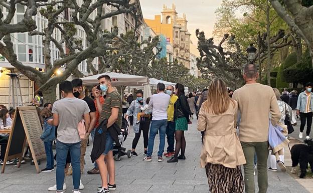 Personas paseando por el Espolón con mascarilla. 