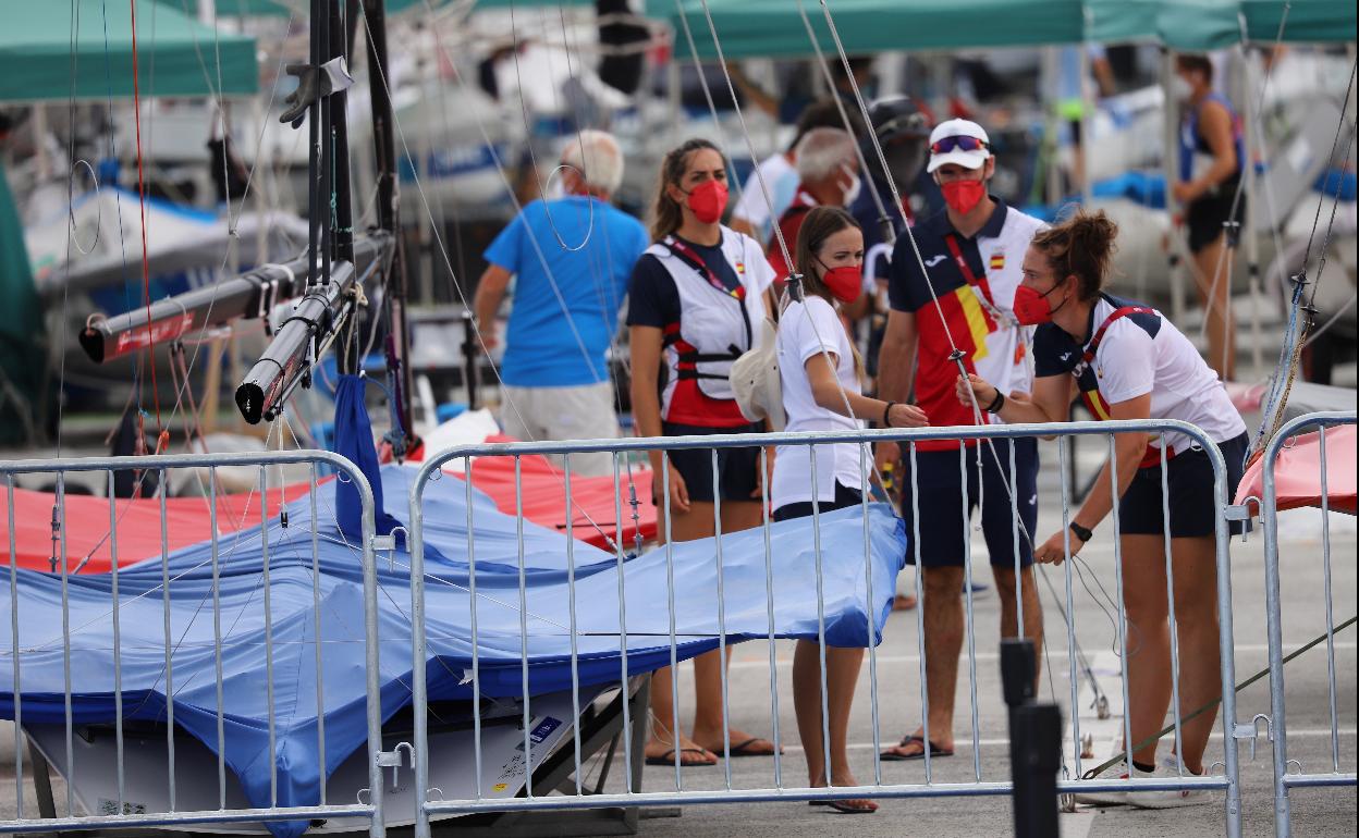 Las regatistas españolas Tamara Echegoyen (derecha) y Paula Barceló (izquierda) recogen sus aparejos tras el aplazamiento de la regata en el puerto de Enoshima.