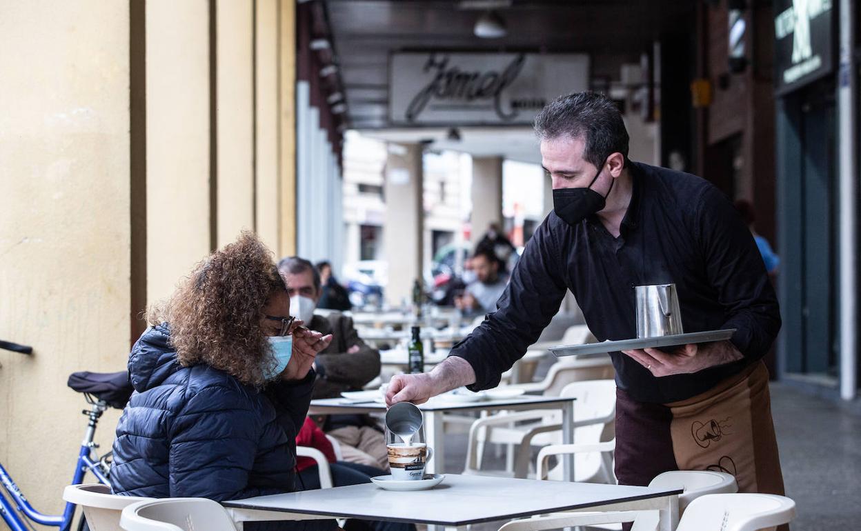 Un camarero sirviendo café en la terraza de un bar en Extremadura. 