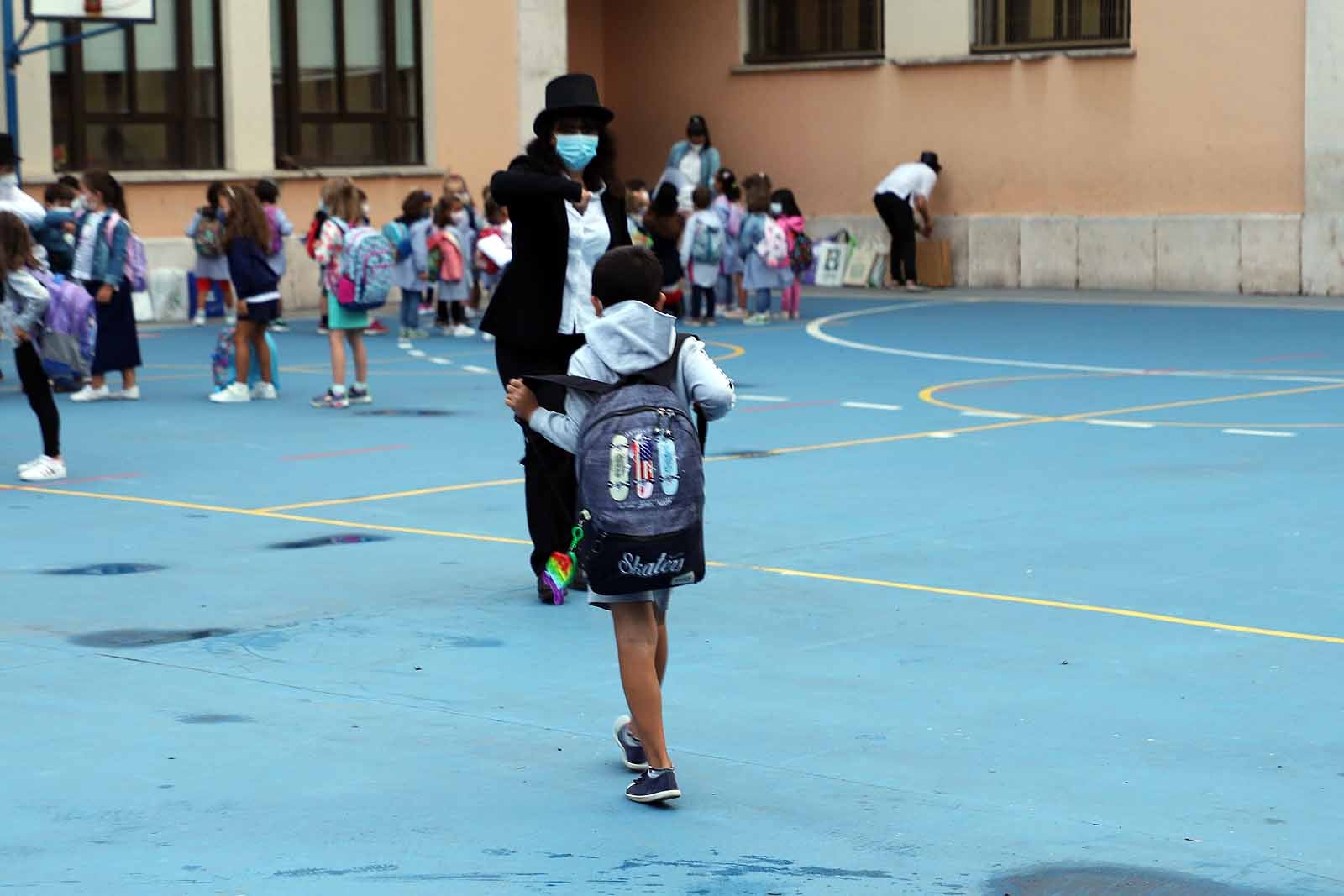 Una profesora saluda con el cole a uno de sus alumnos.