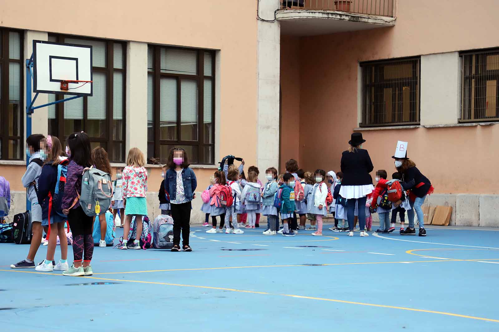 Una profesora saluda con el cole a uno de sus alumnos.