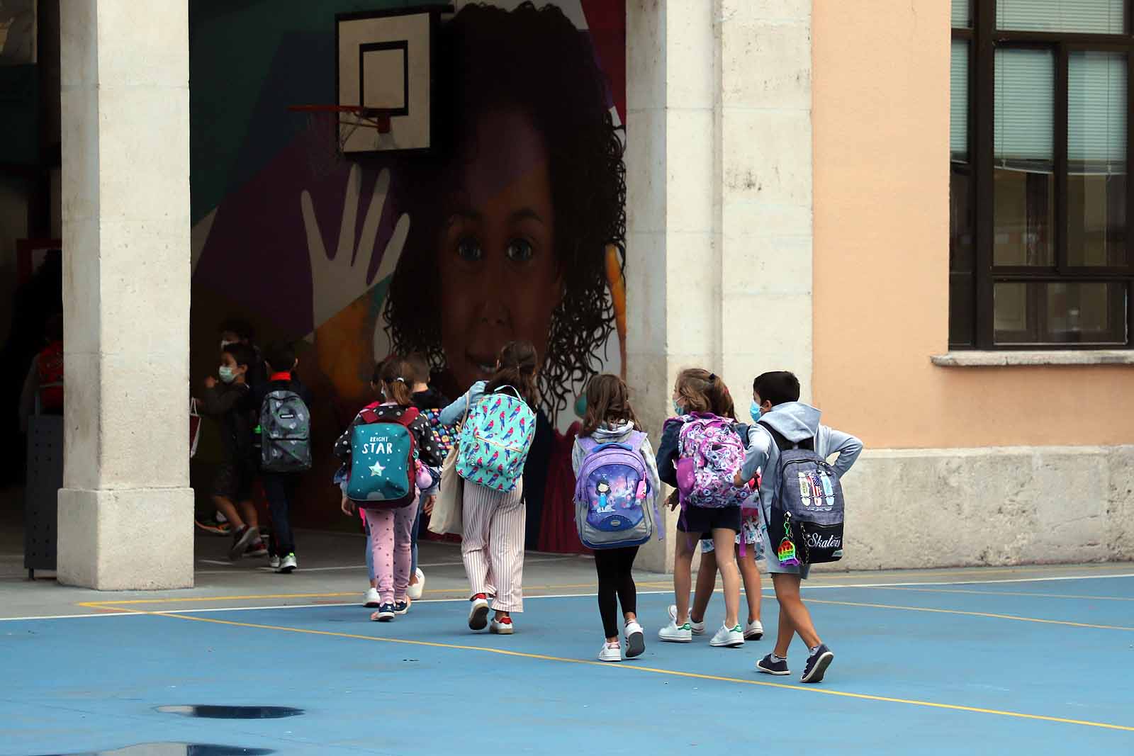 Una profesora saluda con el cole a uno de sus alumnos.