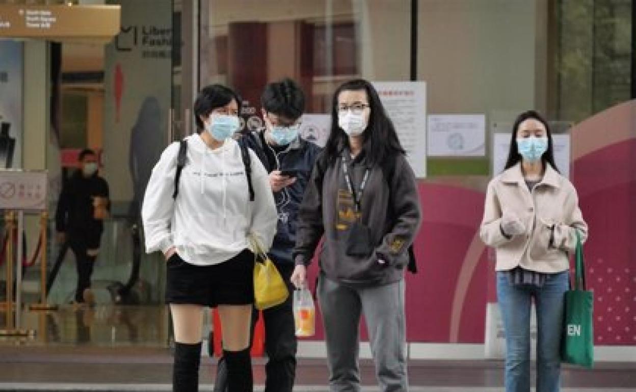 Pasajeros esperan con mascarillas en una estación de tren de China 