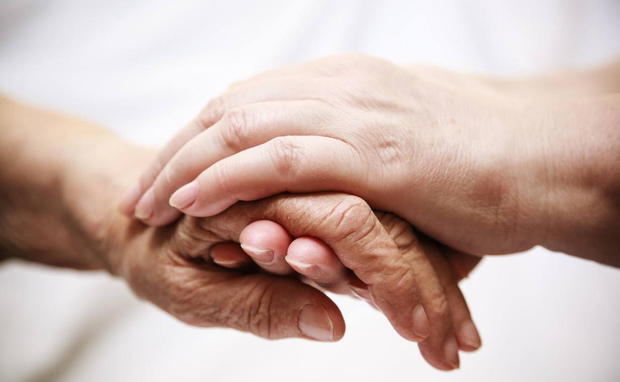 Una mujer sujeta la mano de una paciente. 