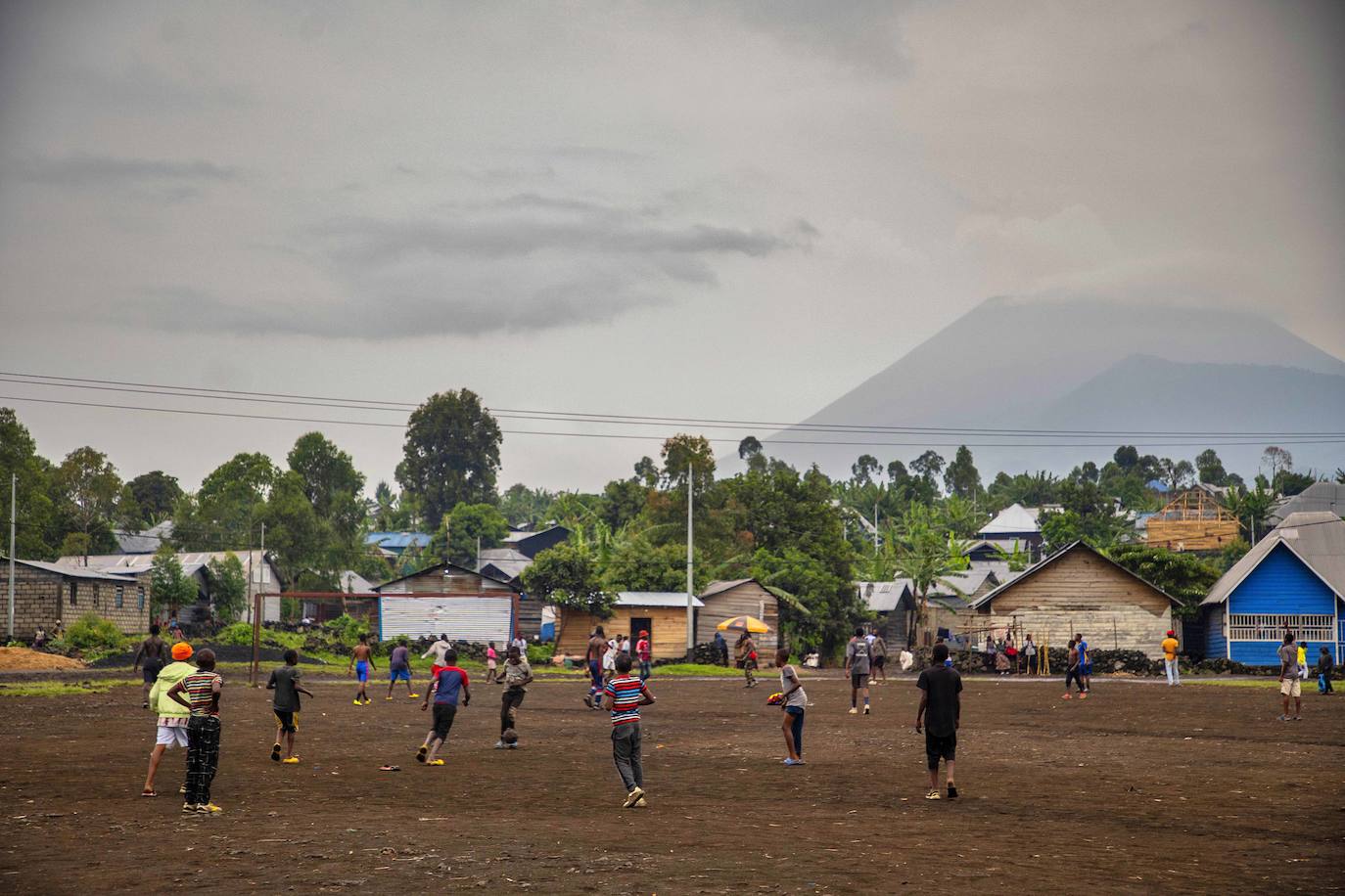 Jóvenes entranan al fútbol en Ngangi Don Bosco con el volcán Nyiragongo al fondo en Goma (Congo)