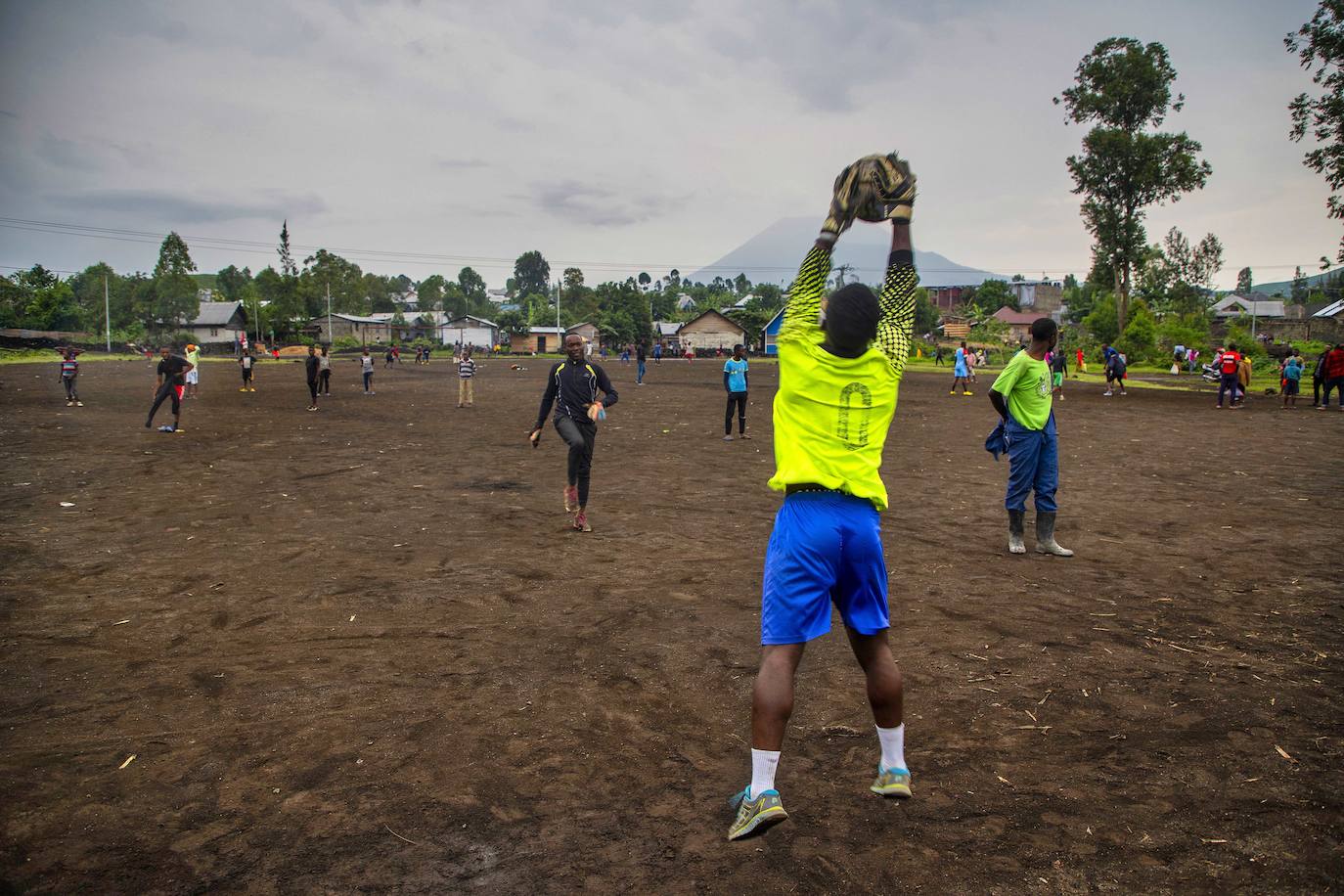 Jóvenes entranan al fútbol en Ngangi Don Bosco con el volcán Nyiragongo al fondo en Goma (Congo)