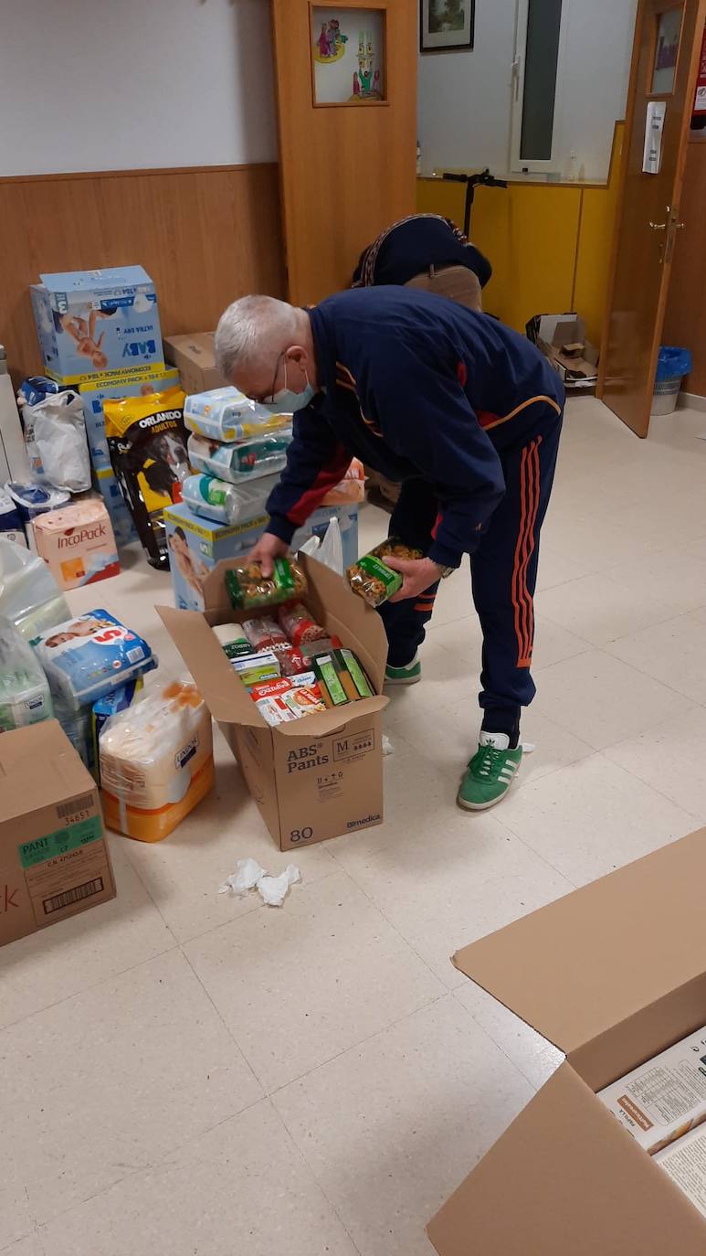 Un voluntario empaqueta alimentos donados para Ucrania en una caja 