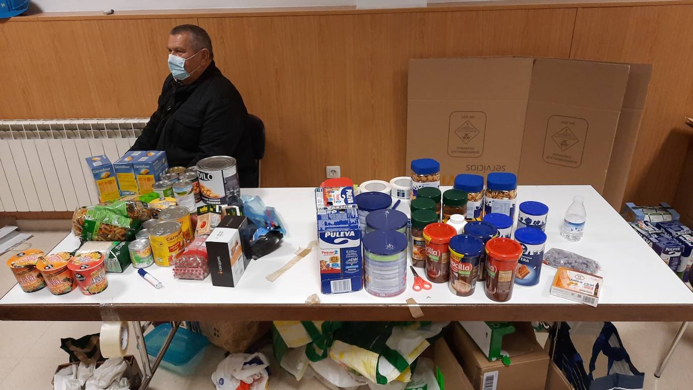 Un voluntario empaqueta alimentos donados para Ucrania en una caja 