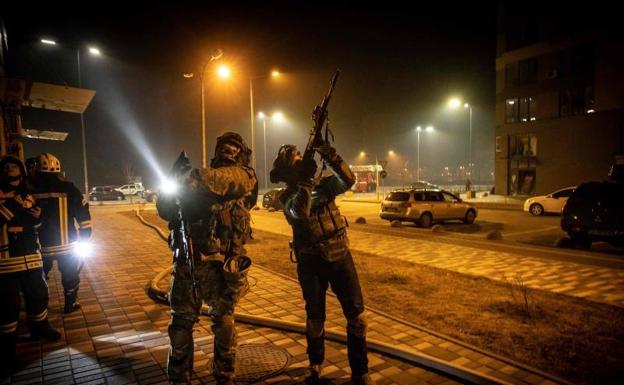 Miembros de las Fuerzas de Defensa Territorial de Ucrania apuntan con su rifle a un posible dron cerca de un edificio residencial.