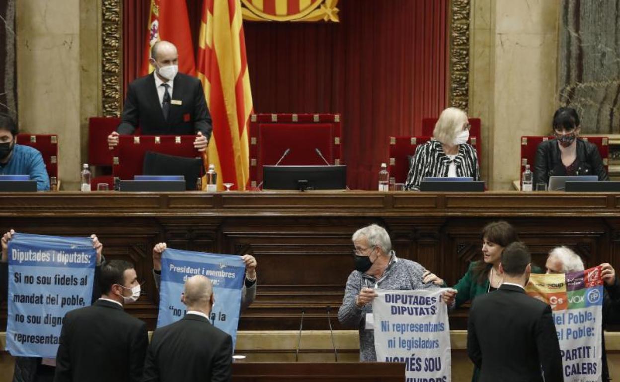 Un grupo de activistas irrumpe en el Parlament con pancartas contra políticos. 