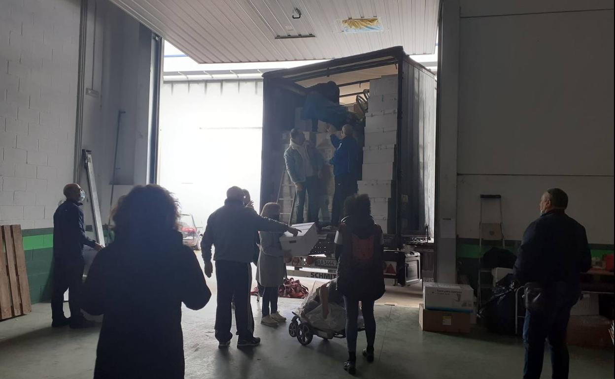 Voluntarios cargan el camión con los palés de donativos almacenados en la nave cedida en el polígono de Villafría