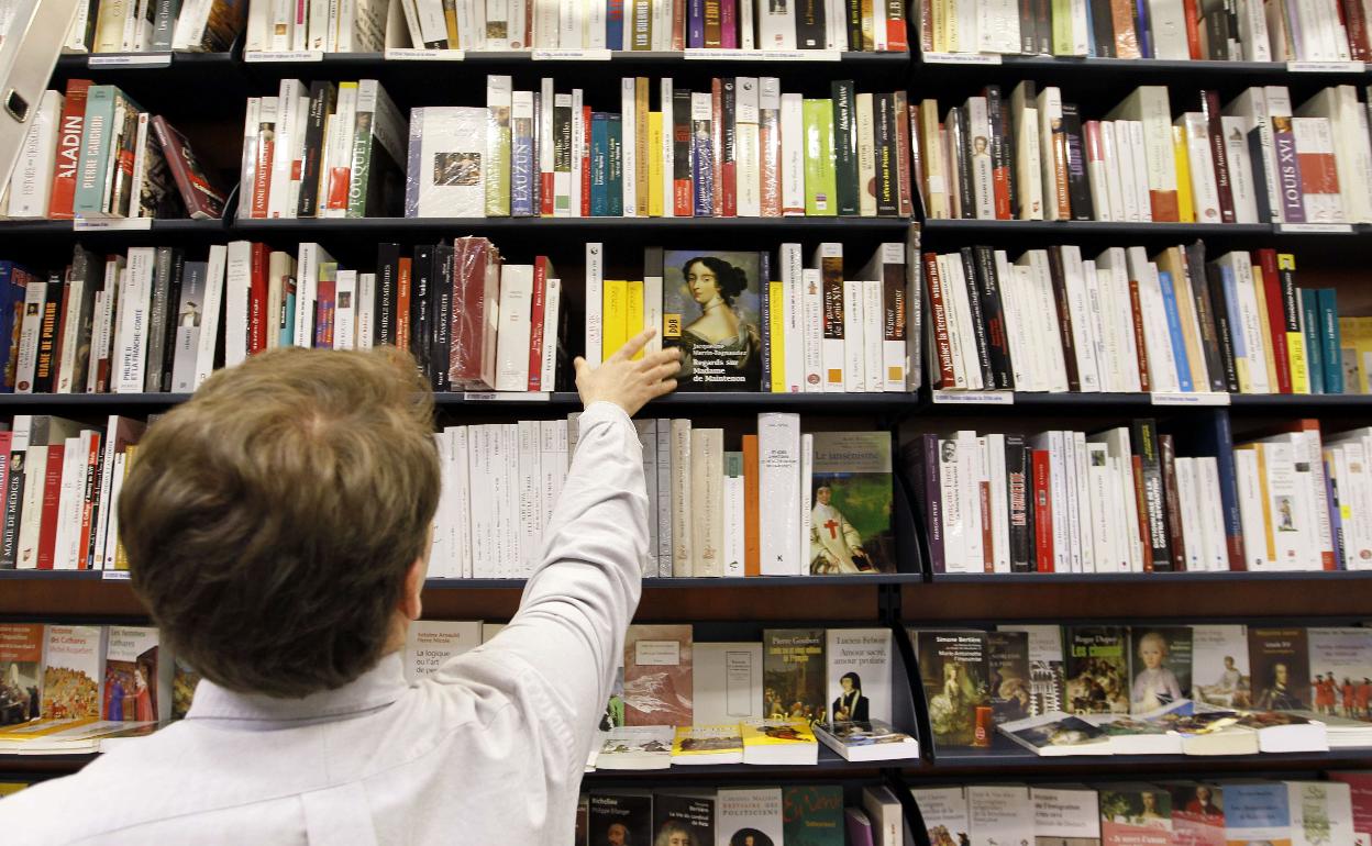 Un niño mira libros en una estantería.