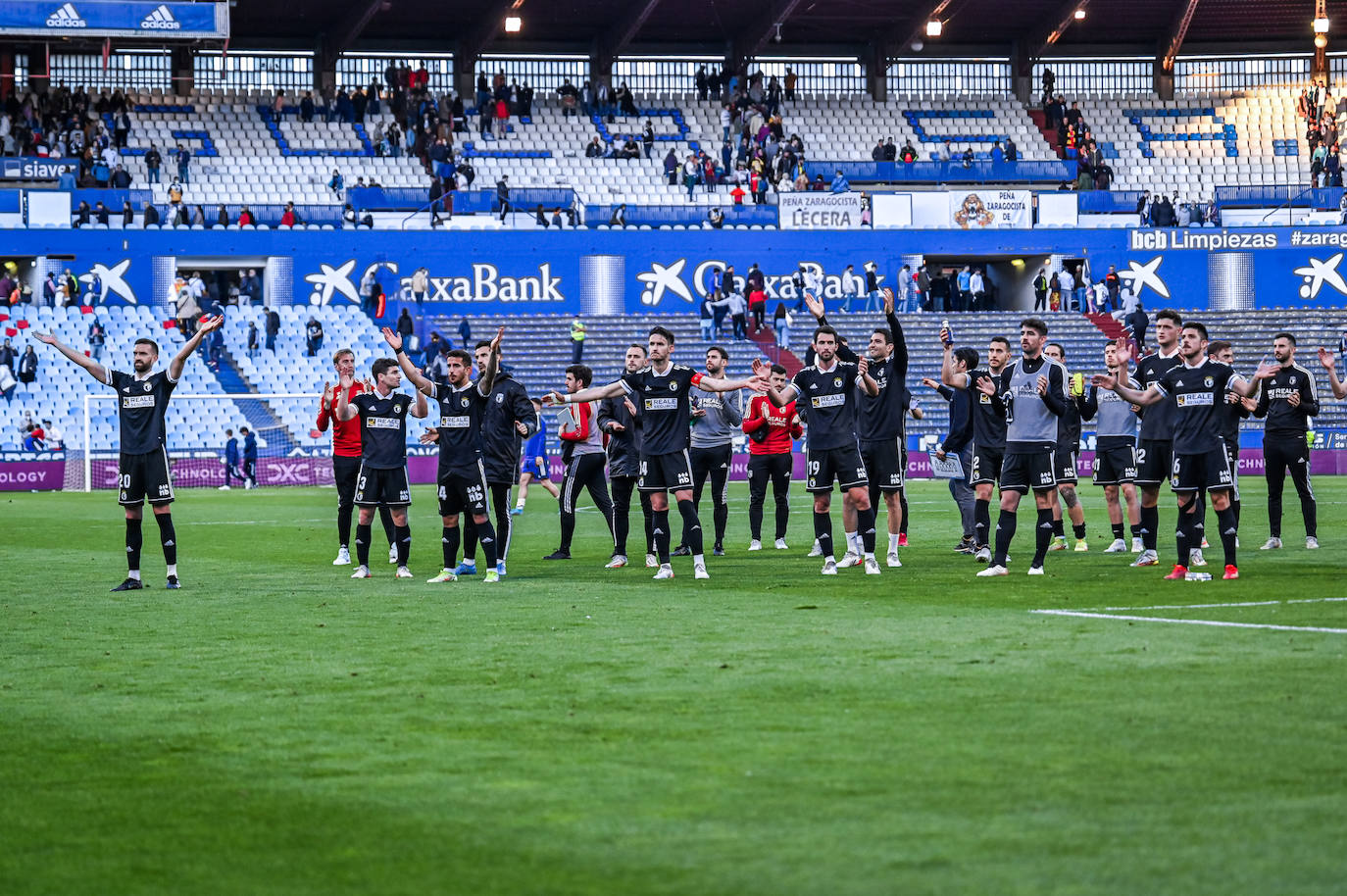 La plantilla del Burgos CF celebra con su afición el punto conseguido en La Romareda.