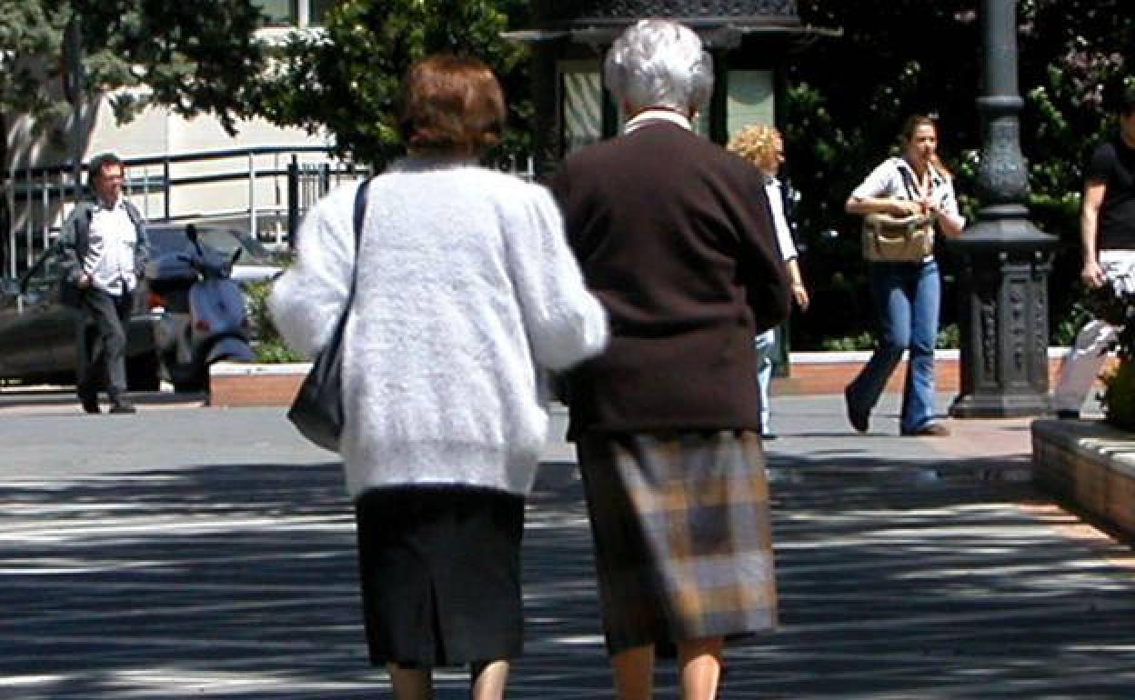 Personas mayores pasean por un parque. 