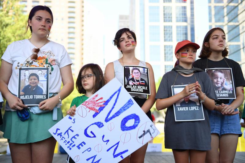 Niños con fotografías de las víctimas del tiroteo en Uvalde participan en un minuto de silencio frente a la Asociación Nacional del Rifle.