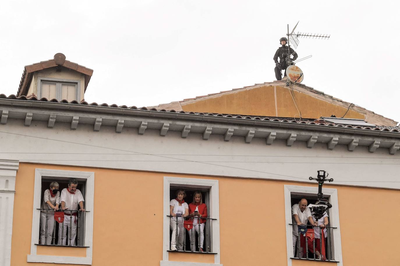 Un policía vigila desde el tejado de una casa la Plaza Consistorial, mientras los vecinos llevan los balcones apra disfrutar del chupinazo 2022.