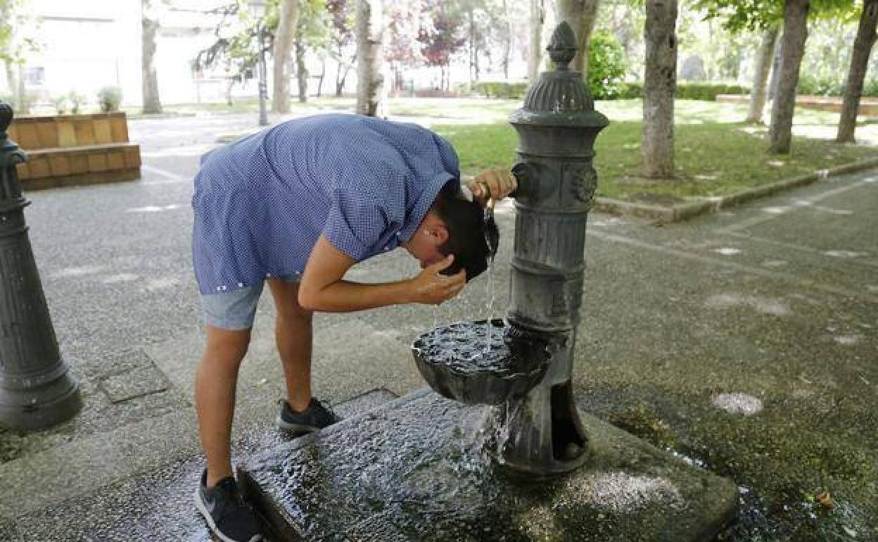 Un hombre se refresca en una fuente.