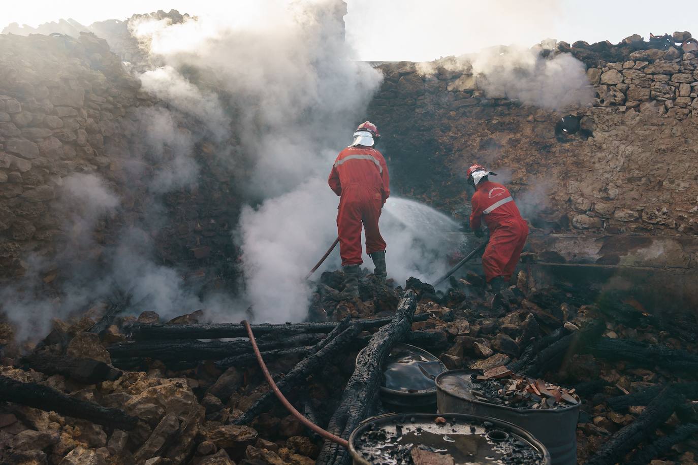 Bomberos trabajando en la extinción de una de las viviendas calcinadas por el fuego.