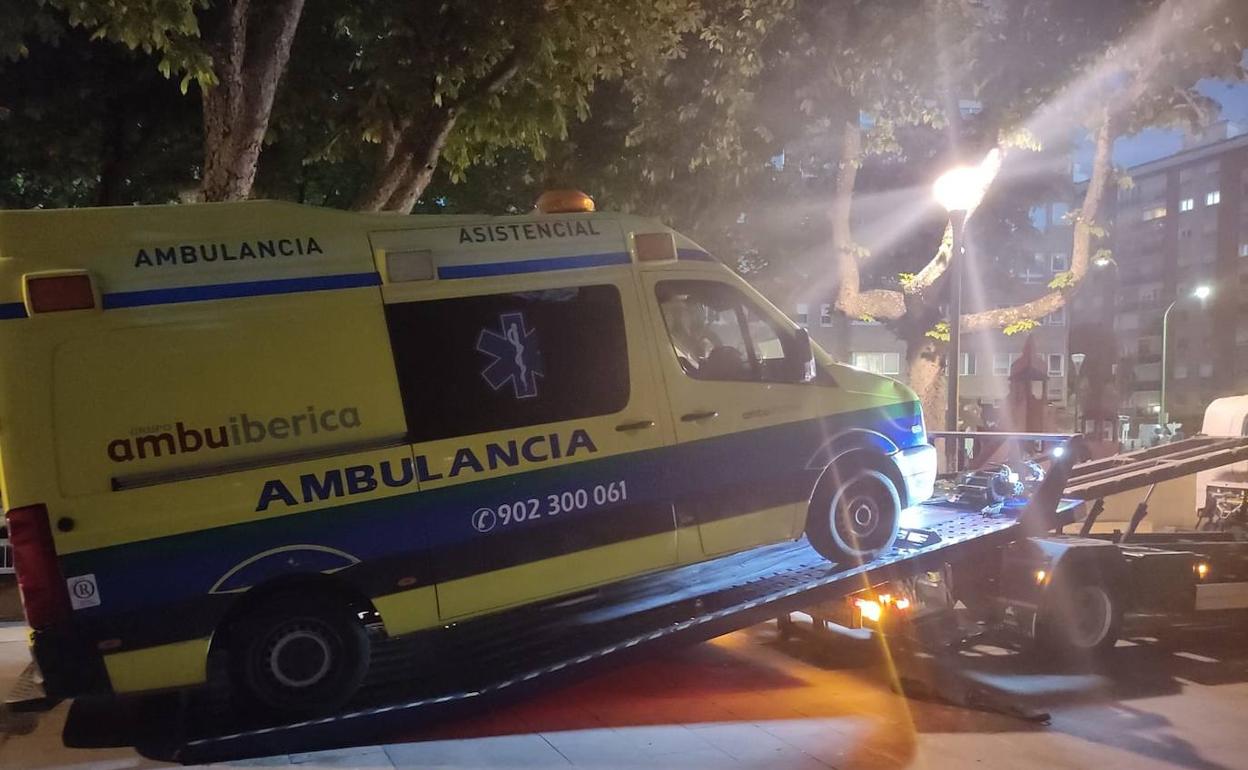 Una ambulacia averiada es trasportada por la grúa al taller. 