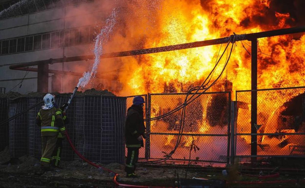 Bomberos intentan sofocar el incendio en una infraestructura energética bombardeada por Rusia en el norte de Kiev. 