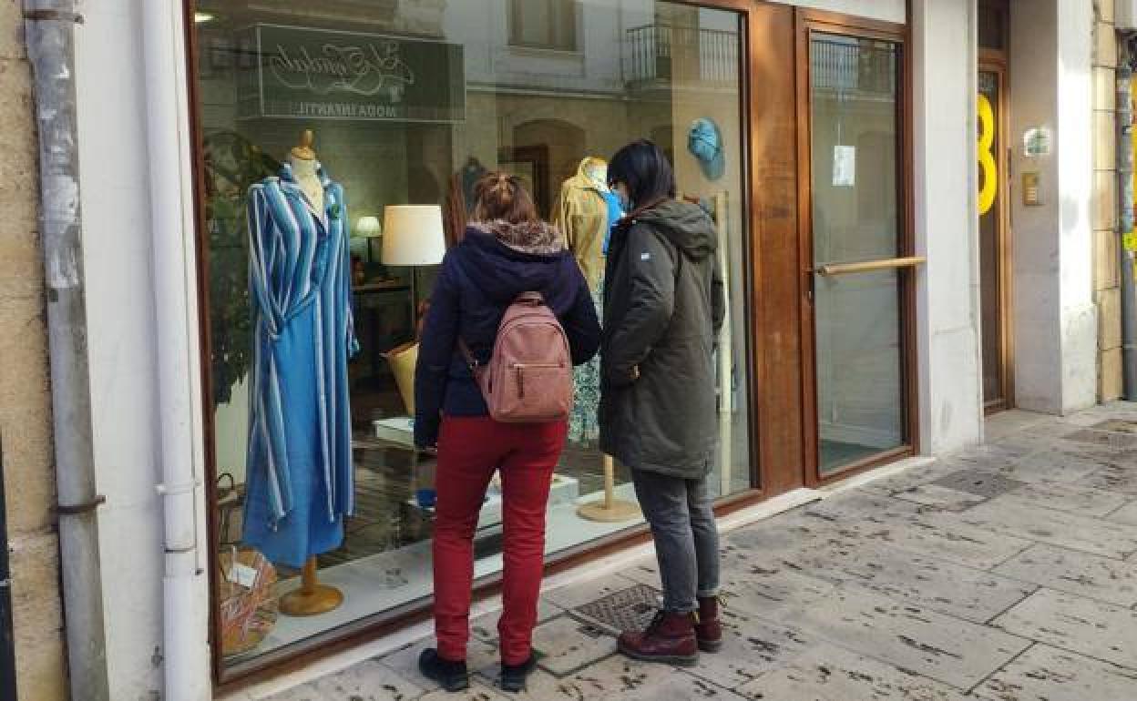 Dos jóvenes miran el escaparate de una tienda de ropa del centro de Burgos