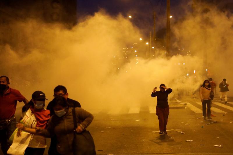 Varios manifestantes escapan de las granadas de gas lanzadas por la Policía en una protesta en Lima