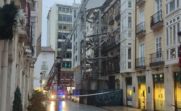 Efectivos de Bomberos de Burgos acordonan la calle mientras verifican el estado del edificio en ruinas subidos a la autoescala del camión desplazado