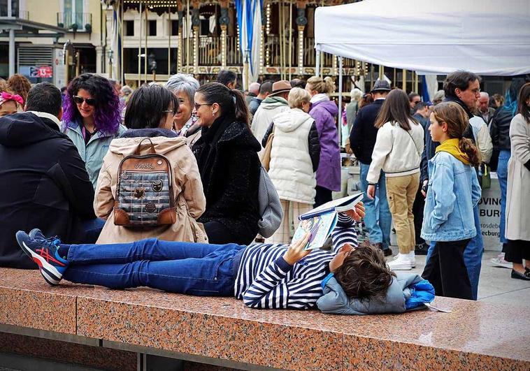 Un niño lee un libro en la plaza Mayor de Burgos donde se encontraba la feria por el Día del Libro.