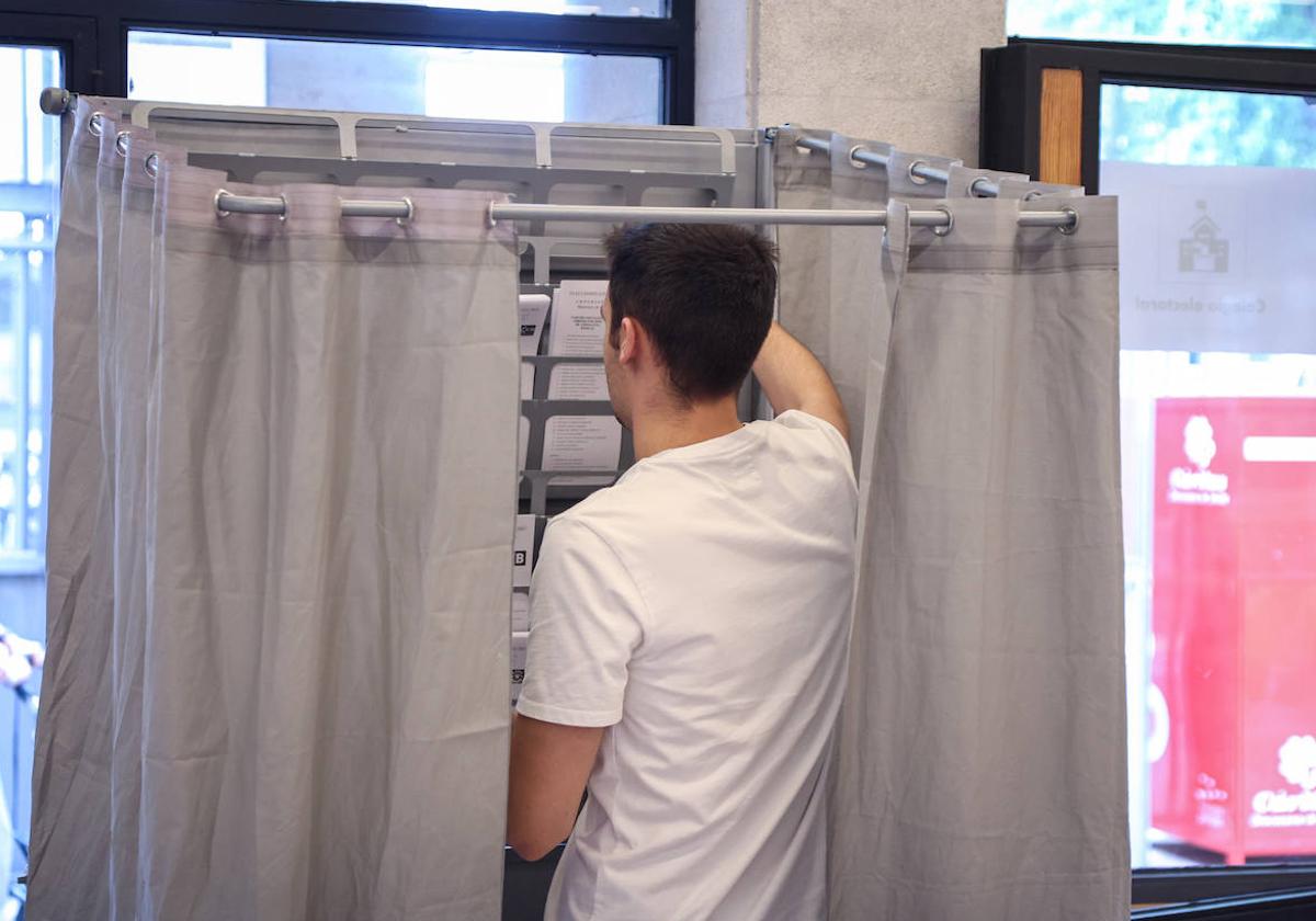 Un hombre coge las papeletas en su colegio electoral.