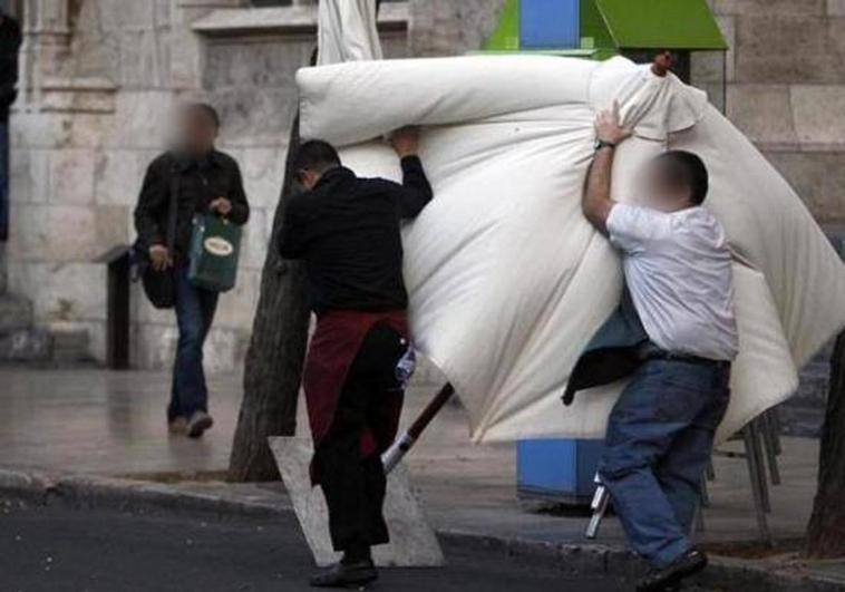 Dos trabajadores luchan contra el viento para recoger una sombrilla en Burgos en una imagen de archivo.