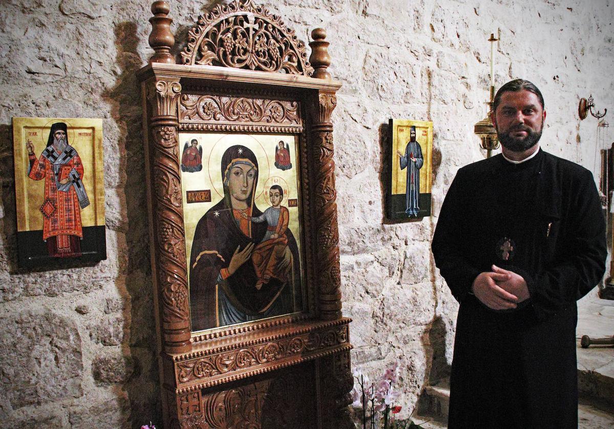 El padre ortodoxo Danut Mures posa frente a algunos iconos que permanecen fijos en la iglesia católica de Villatoro.