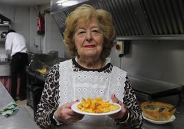 Presen con un plato de patatas bravas en el Mesón Burgos.