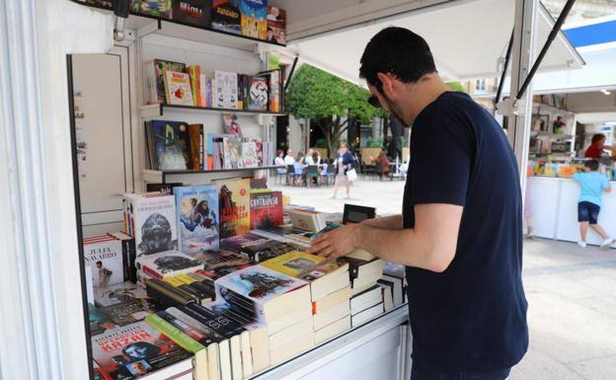 Un librero coloca algunos ejemplares en su puesto de la Plaza Mayor de Burgos durante la Feria del Libro de junio.