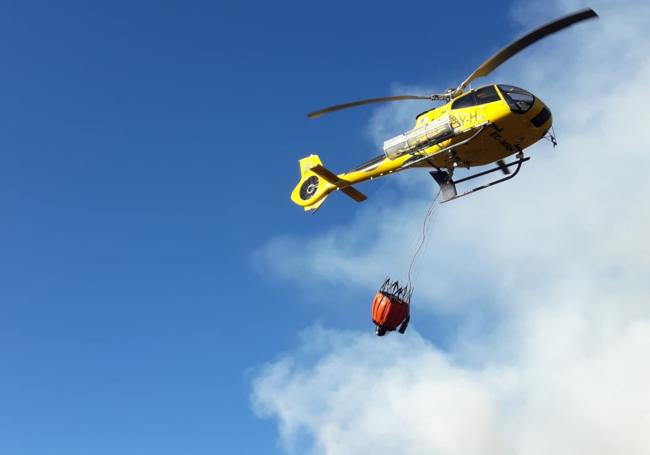 El helicóptero transporta agua para sofocar el incendio.