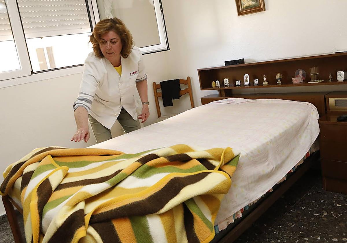 Una auxiliar de ayuda a domicilio realiza tareas domésticas en la vivienda de una anciana.