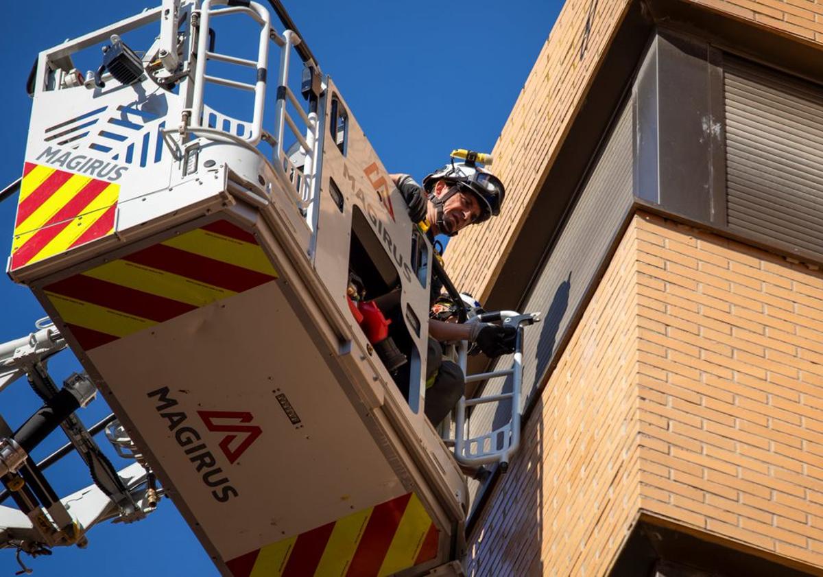 Imagen principal - Los Bomberos de Burgos trabajan para acceder a una casa por la ventana.