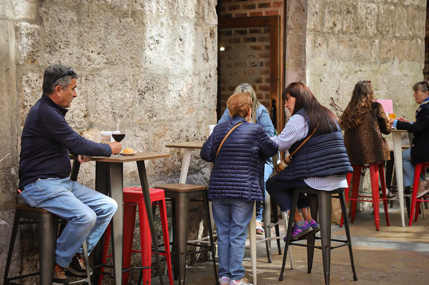 Gente disfrutando de una tapa y bebida en el exterior de un local de la calle San Lorenzo