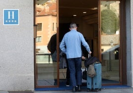 Un turista entra con su maleta en un hotel.