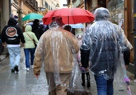 Imagen de archivo de personas paseando protegiéndose de la lluvia.