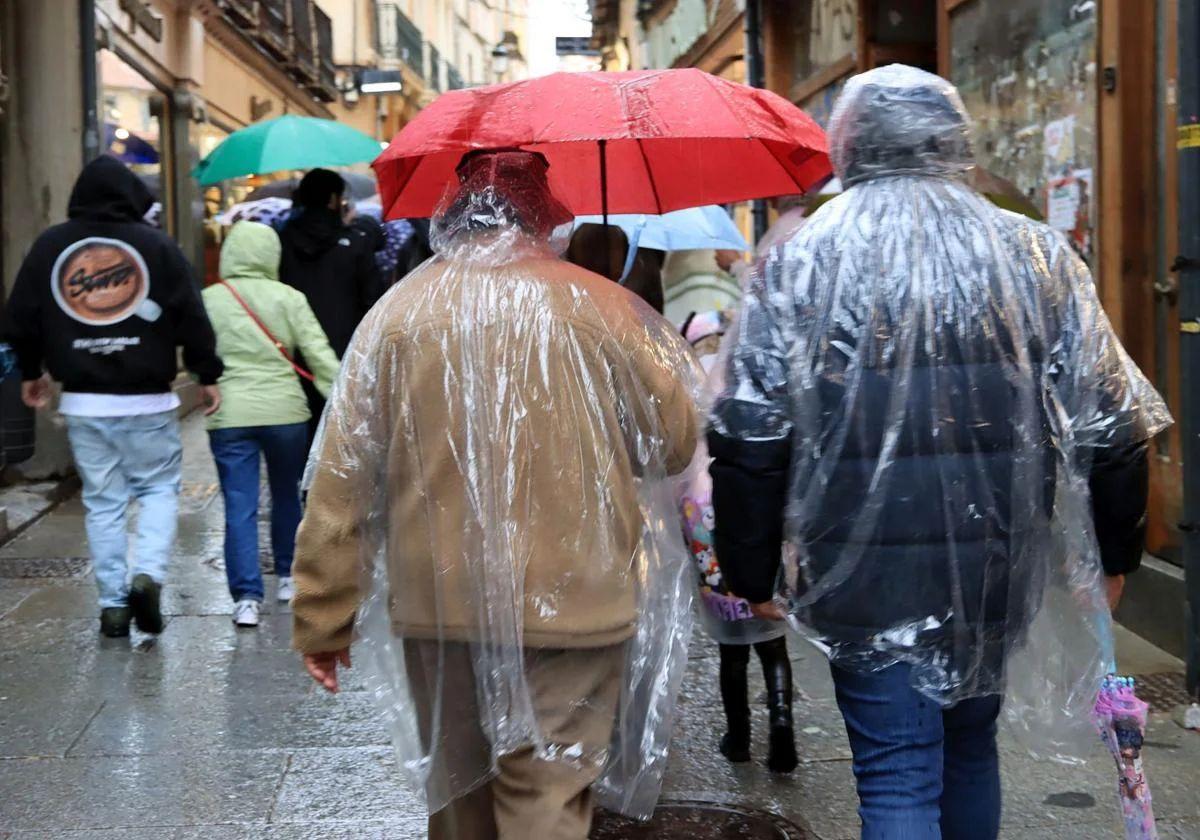 Imagen de archivo de personas paseando protegiéndose de la lluvia.