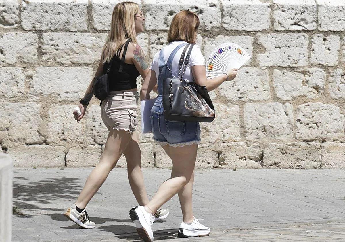 Dos mujeres se abanican mientras caminan.