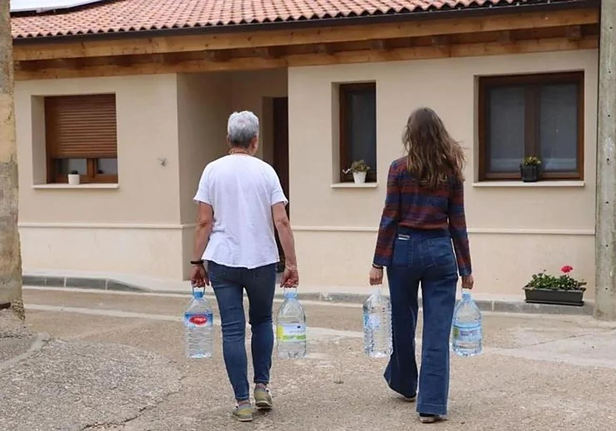 Dos personas recogen garrafas de agua en Grijalba, Burgos.