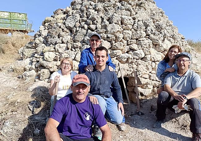 Los voluntarios posan con una de las cabañas que restauraron.