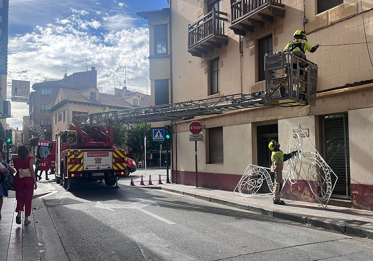 Los Bomberos de Aranda de Duero retirando y recolocando las luces que han caido.