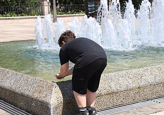 Niño refrescándose en una fuente de Burgos.