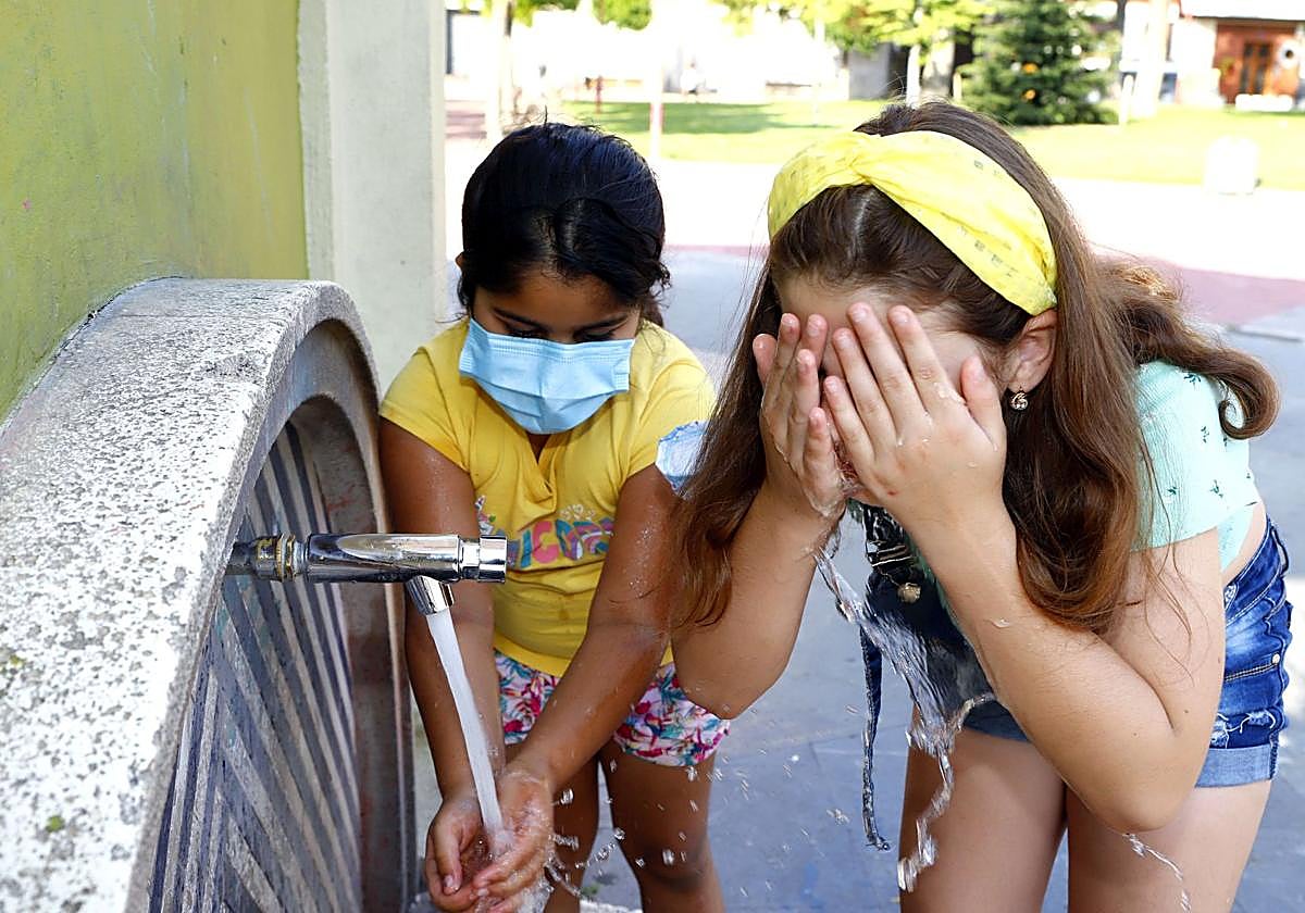 Dos niñas se refrescan en una fuente de Miranda por el calor.