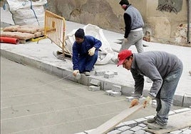 Un grupo de operarios migrantes trabaja en labores en una calzada.