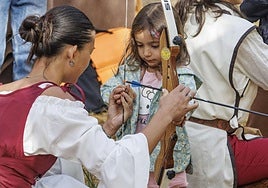 Una niña aprende a como lanzar una flecha con un arco